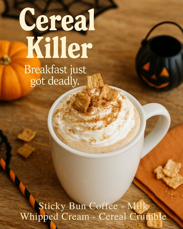 A white mug of Sticky Bun Flavored Coffee with whipped cream and cereal bits sits on a wooden table near a pumpkin and black jack-o-lantern, striped straw beside it. Text: